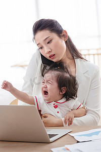 伤心妈妈摄影照片_年轻妈妈抱着孩子使用电脑