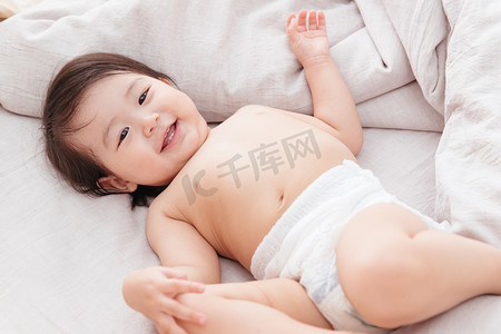 宝宝纸尿裤摄影照片_可爱宝宝躺在床上