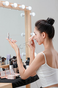 美女照镜子摄影照片_年轻女人在化妆间里化妆