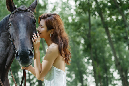 眼睛度假摄影照片_漂亮自信的青年女人和马