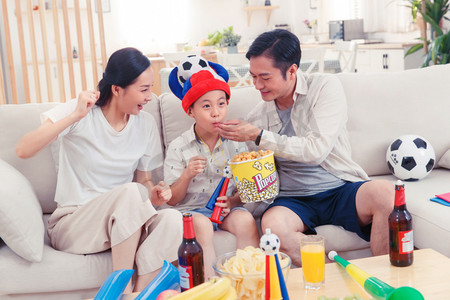 电视足球摄影照片_快乐的一家人边看电视边吃零食