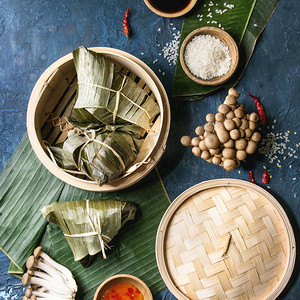 亚洲大米 piramidal 从大米木薯粉中配以竹蒸笼为食的香蕉叶制成的包子。配料, 调味汁。蓝色纹理背景。顶部视图。方形图像