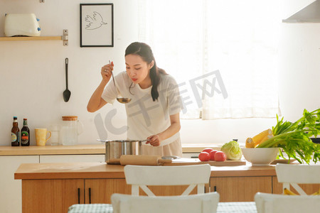 家务劳动摄影照片_青年女人在厨房里做饭