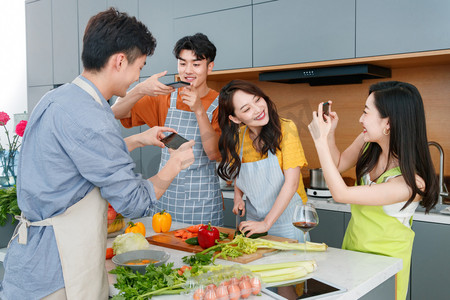 帆布围裙摄影照片_快乐的年轻人在厨房做饭照相