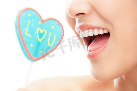 蓝色人物摄影照片_准备吃心型棒棒糖的青年女人嘴部特写