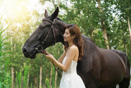 眼睛度假摄影照片_穿裙子的漂亮女人牵着马