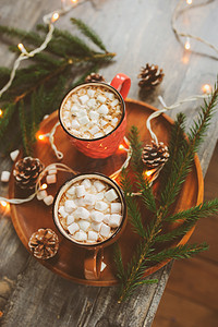 top view of hot cocoa with marshmallows on rustic wooden table with christmas lights. Cozy winter home concept
