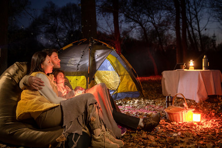 幸福的一家三口夜晚在野外露营