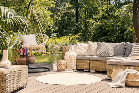 一个大阳台与舒适的休闲沙发与垫子, 一张桌子和一个字符串摆动在一个绿色的花园, 在阳光明媚的假期.