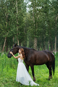 眼睛度假摄影照片_户外穿婚纱的青年女人和马