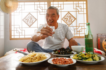 老年人坐在家里喝酒吃饭