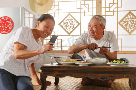 老年夫妇在家里吃饭看手机
