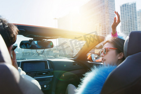 皮毛女人摄影照片_时尚的青年伴侣驾驶跑车兜风