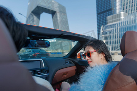皮毛女人摄影照片_时尚的青年女人坐在副驾驶兜风