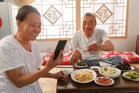 吃饭乡村摄影照片_老年夫妇在家里吃饭看手机
