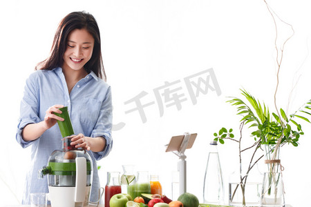 榨果汁摄影照片_青年女人在线直播榨果汁