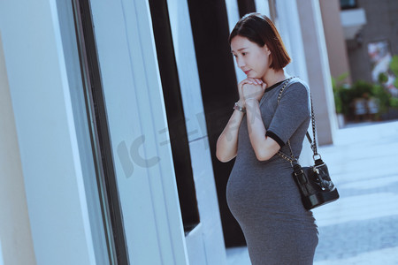 孕妇站在商店橱窗前