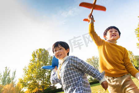 拿着玩具飞机在公园玩耍的男孩