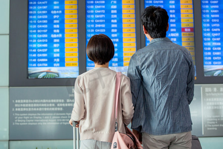 青年情侣在机场候机厅看航班表
