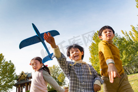 的男孩摄影照片_拿着玩具飞机在公园玩耍的快乐儿童
