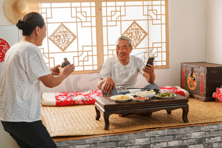 老年夫妇在家里吃饭看手机