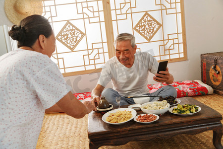 吃饭乡村摄影照片_老年夫妇在家里吃饭看手机