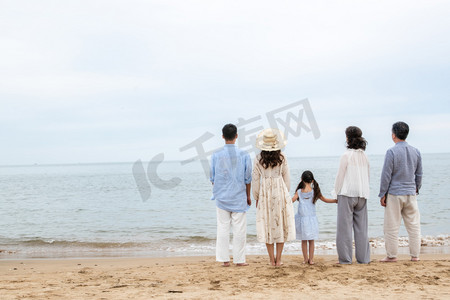 海滩游玩摄影照片_快乐的一家人站在海滩上