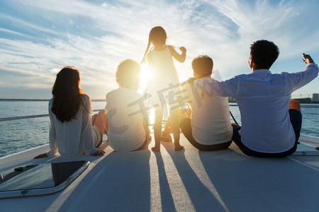 五个人摄影照片_夕阳下坐在游艇上的快乐一家人