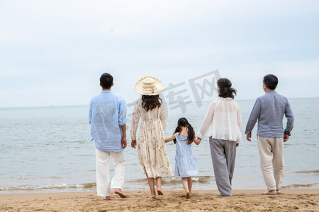 沙滩背影摄影照片_快乐的一家人站在海滩上