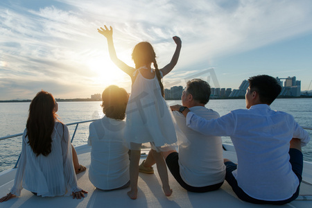夕阳下坐在游艇上的快乐一家人