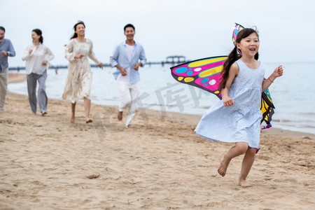 海滩游玩摄影照片_快乐的一家人在海滩上放风筝