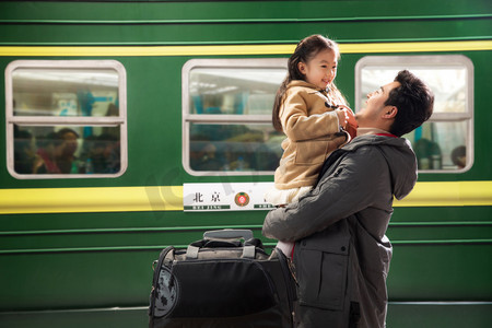 父亲抱着女儿站在火车站站台上