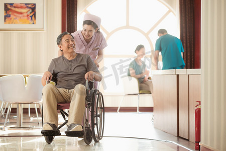 摄影照片_护士推着坐轮椅的老年人