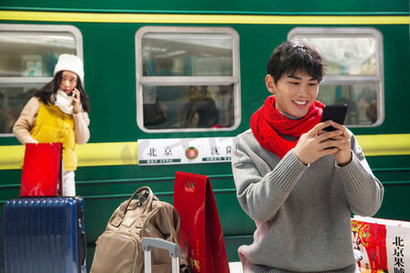 春运视频摄影照片_在火车站台上看手机的青年男人