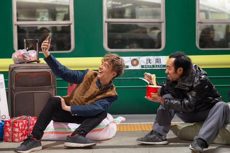 两名男子在火车月台上看手机