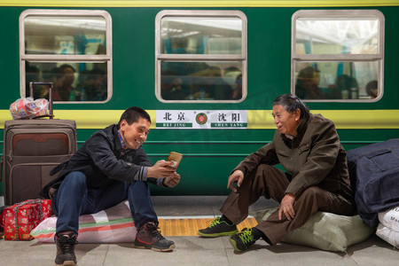 怀旧过年摄影照片_两名男子在火车月台上看手机