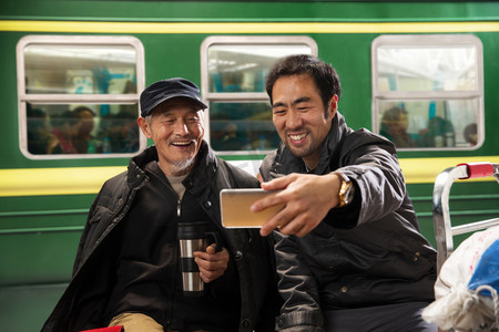 怀旧过年摄影照片_在火车站台上看手机的旅客