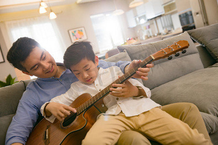 快乐学习的亲子摄影照片_父亲和男孩在弹吉他