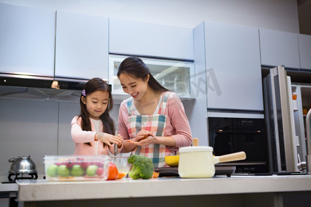 妈妈教孩子做饭摄影照片_年轻妈妈和女儿在厨房