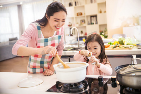 劳动课摄影照片_年轻妈妈和女儿在厨房