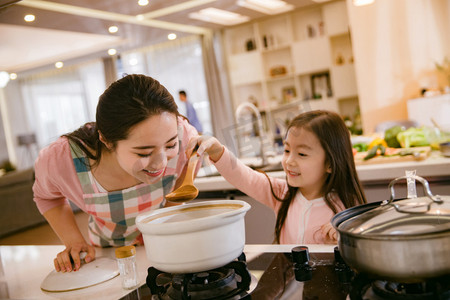 妈妈教孩子做饭摄影照片_年轻妈妈和女儿在厨房