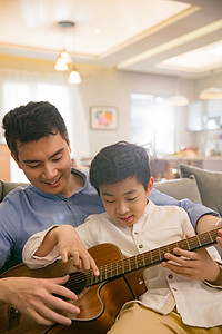 快乐学习的亲子摄影照片_父亲和男孩在弹吉他