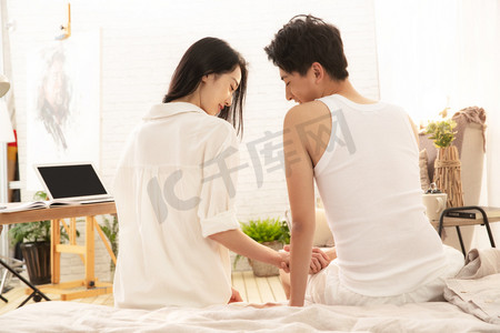 幸福的情侣坐在床上交流的背影