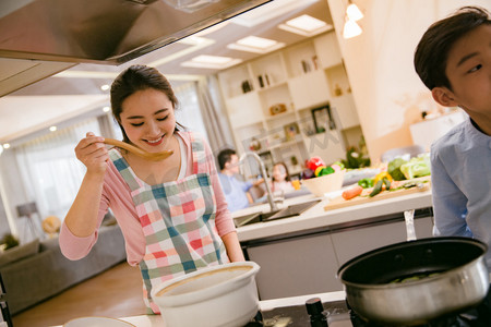 妈妈教孩子做饭摄影照片_年轻妈妈和儿子在厨房