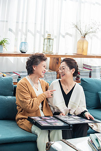 快乐的中老年生活摄影照片_快乐的老姐妹坐在沙发上看相册