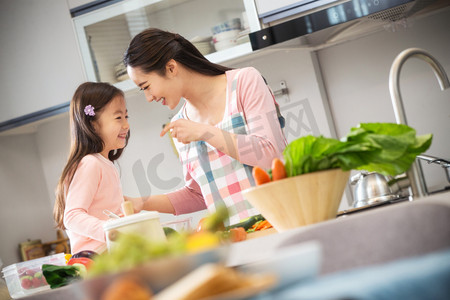 义务教育劳动摄影照片_年轻妈妈和女儿在厨房