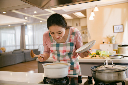 煲汤摄影照片_青年女人在厨房煲汤