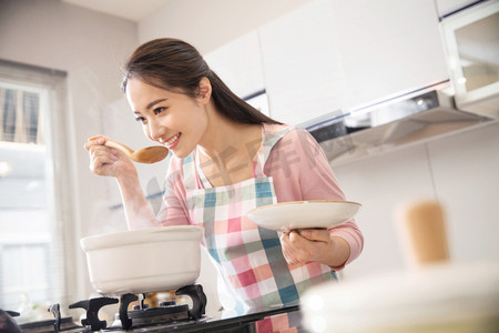 煲摄影照片_青年女人在厨房煲汤