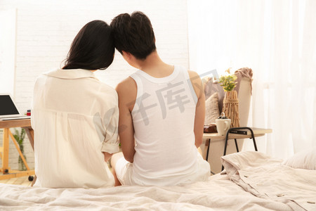 浪漫情侣背影摄影照片_幸福的情侣坐在床上的背影