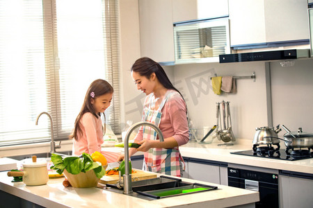妈妈教孩子做饭摄影照片_年轻妈妈和女儿在厨房